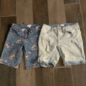 One of these pairs of shorts has daisy flowers and the other one has unicorns.